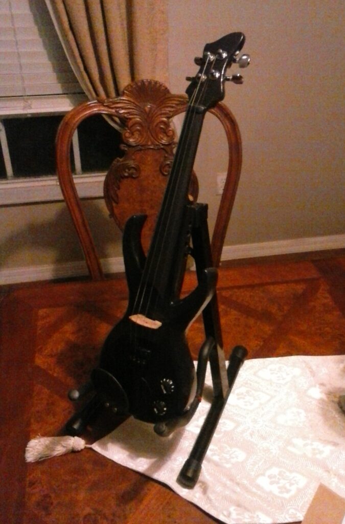 Stratocaster inspired electric violin built and hand-carved from scratch out of red oak, a passive piezo pickup and other electric components, guitar tuning pegs. Black in color.