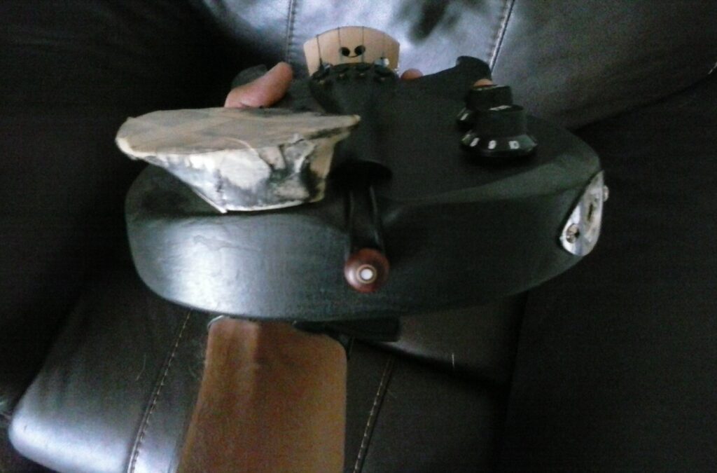 Stratocaster inspired electric violin built and hand-carved from scratch out of red oak, a passive piezo pickup and other electric components, guitar tuning pegs. Black in color. Unpainted.