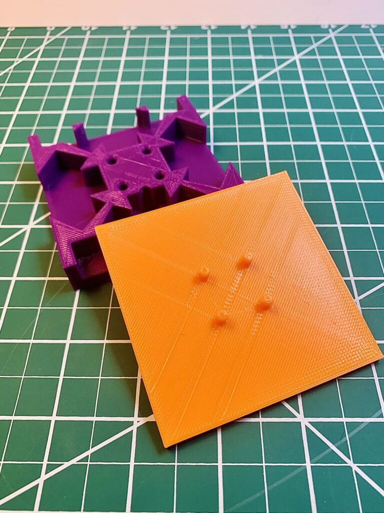 A 3D Modeled and 3D Printed Free body diagram, FBD, practice activity for Physics students. This image is it with a purple base and a orange cap. Intricate inner designs allows for the vectors to be placed at angles too. 