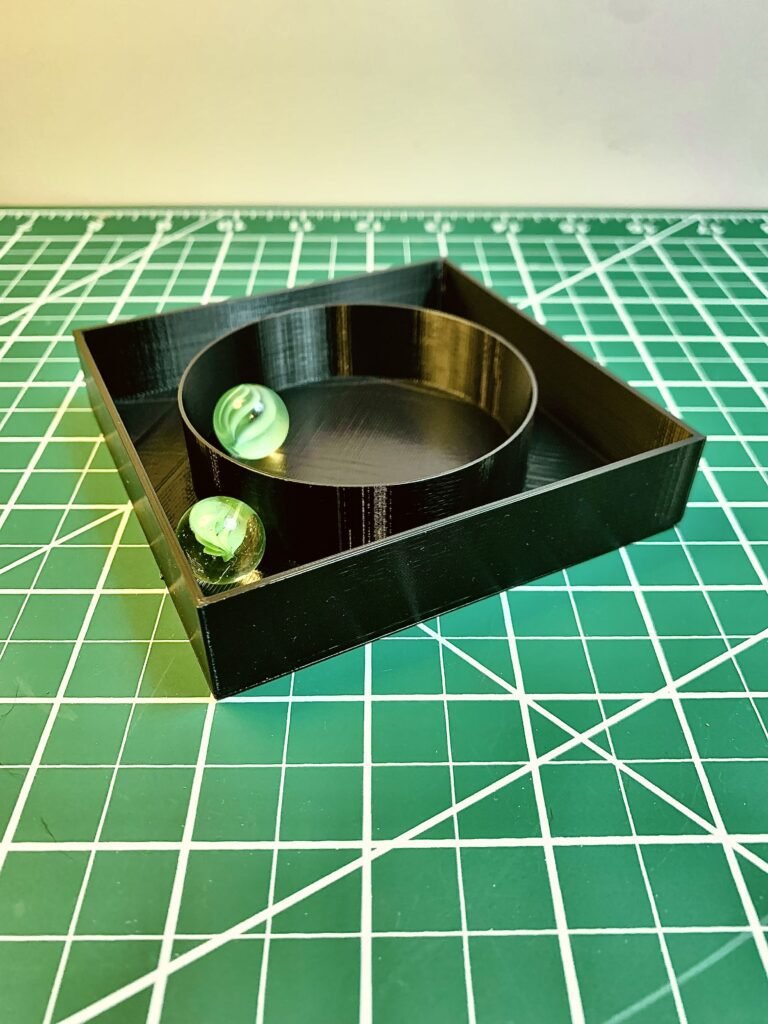 3D Printed Mystery box activity. It's 3D printed rectangular box with different fin designs on the inside and a marble. This one has a circle and 2 marbles. 