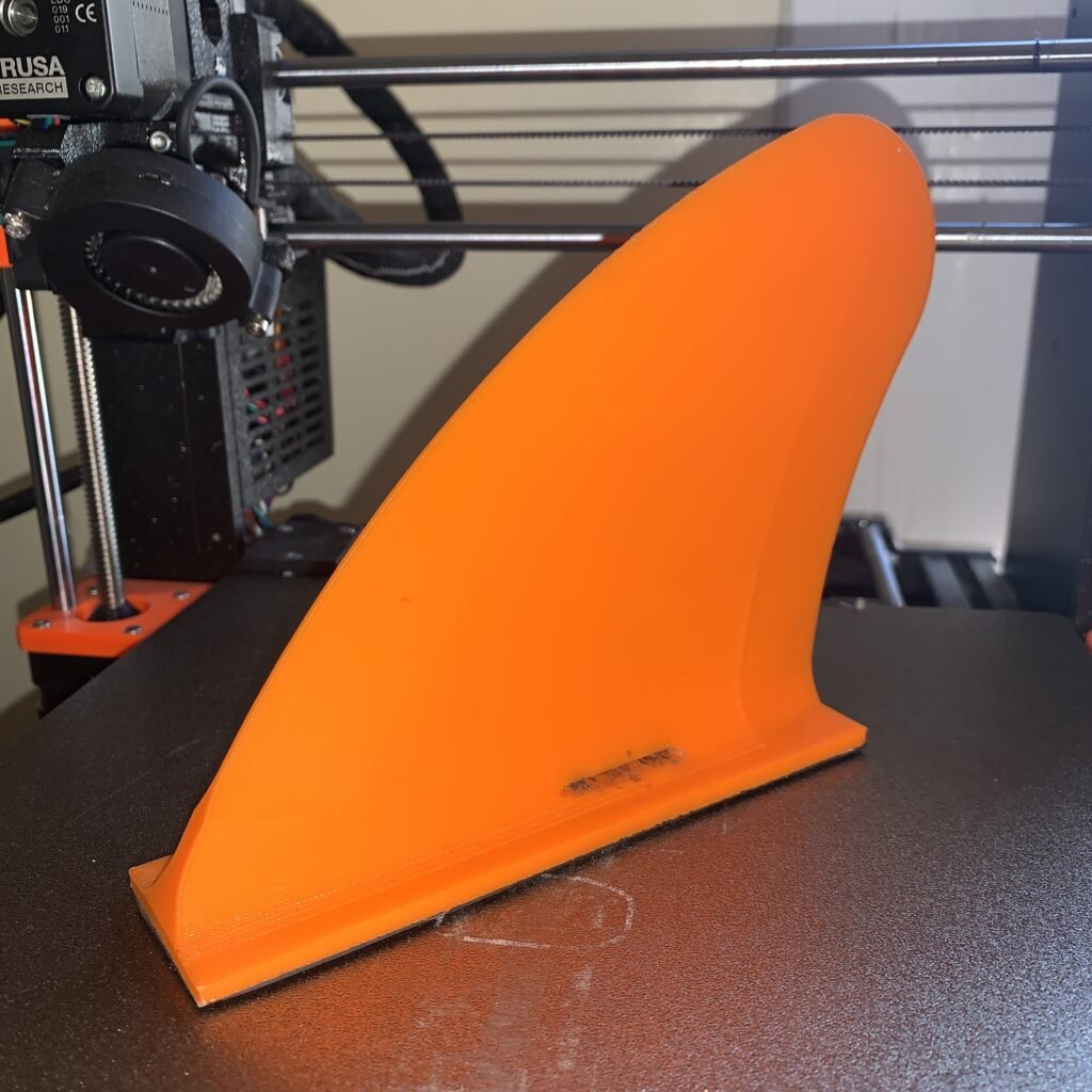 Orange 3D modeled and 3D printed fin for a whitewater Hydra kayak. This design requires you to ratchet strap it to the hull via a small slot on the bottom near the base.