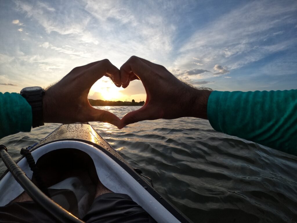 Kayaking the Intercoastal on the Indian River Lagoon. I am making a heart with my hands around the setting sun. Image with a filter. 