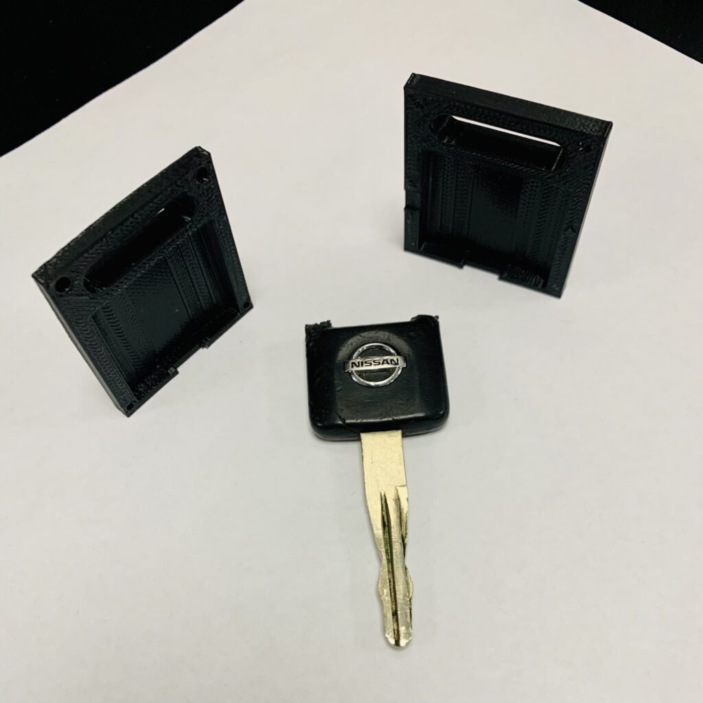 Nissan car key fob with a broken loop. I 3D modeled and 3D printed a case that encloses the key and gets glued together so that it can be clipped to a keychain again. 