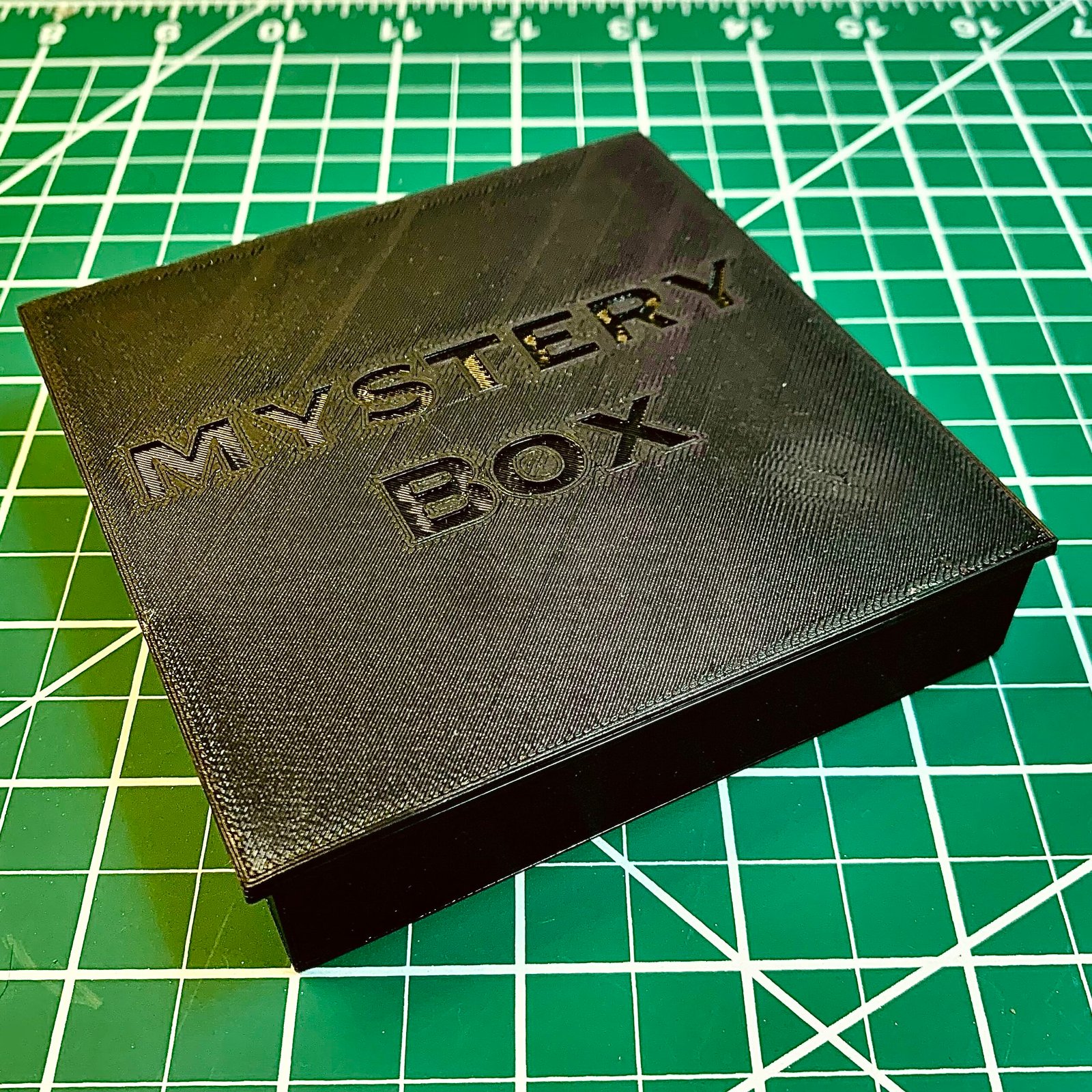 3D Printed Mystery box activity. It's 3D printed rectangular box with different fin designs on the inside and a marble. This image is of it enclosed with the cap. The cap says "Mystery Box."