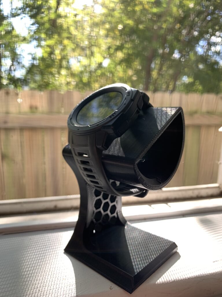 3D printed watch holder, black with a hexagonal pattern on the side. With Garmin watch attached. 