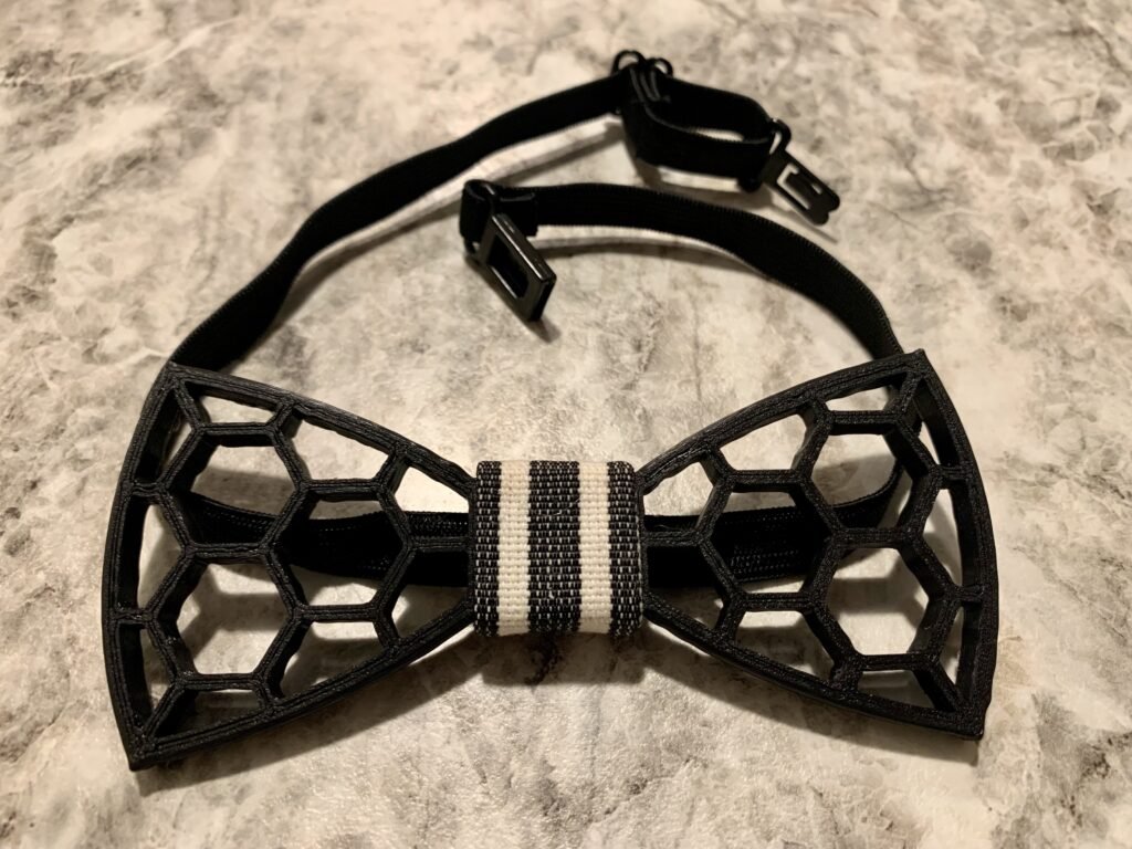 Black 3D printed modeled bow tie with hexagonal patterns. 