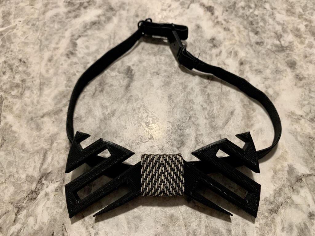 Black 3D printed modeled bow tie with a modern cutout pattern. 