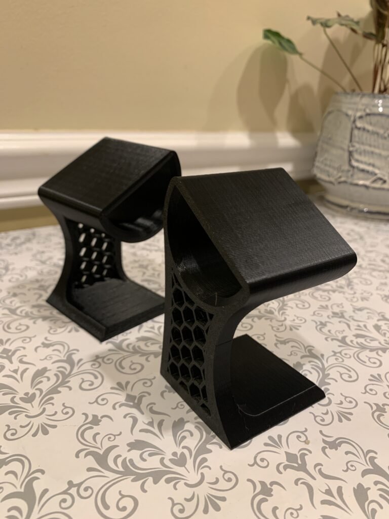 3D printed watch holder, black with a hexagonal pattern on the side.