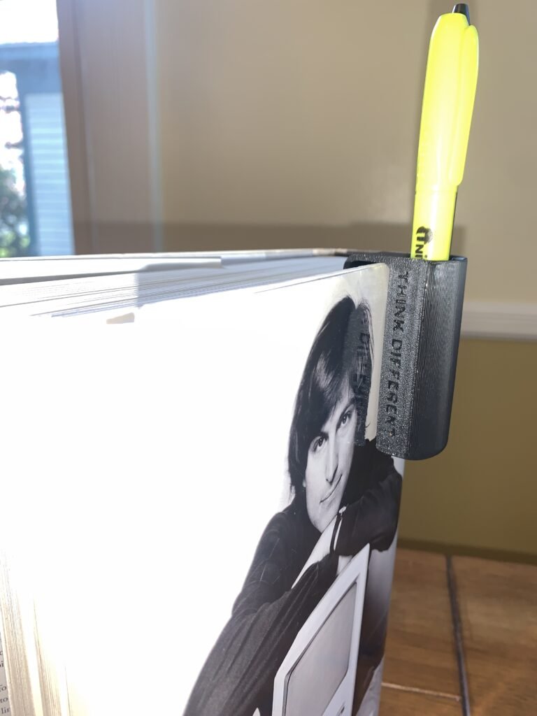 You’re probably wondering…why not simply clip your pen or highlighter to your book? If you’re anyone like me, you write a lot in a book and you prefer to read, when standing or sitting on the couch, or even on the toilet. So instead of selling my pen down on my chest or my ear, I designed an printed a holder that clips into any book and hold a pen and highlighter. 3D Printed Book Pen Holder with Steve Jobs by Walter Isaacson's book