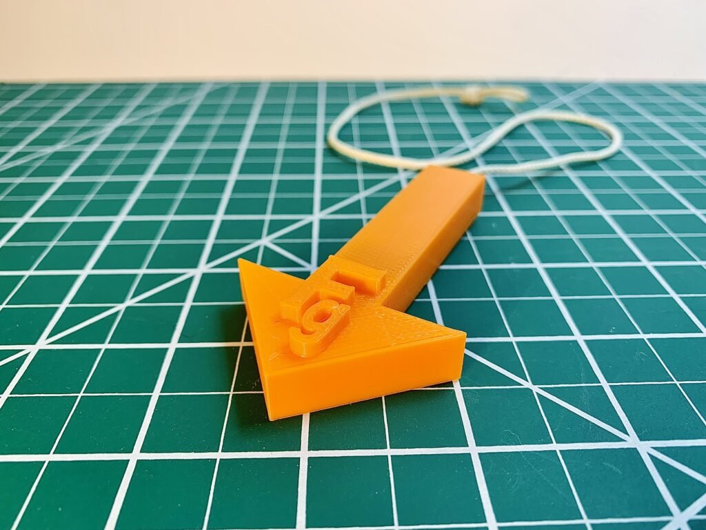 Orange 3D printed plumb bob with the Fg (Force of gravity) label on it to showcase the direction of the gravity vector during physics demonstrations.