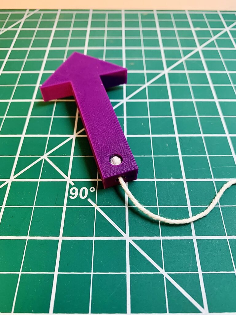 Purple 3D printed plumb bob with the Fg (Force of gravity) label on it to showcase the direction of the gravity vector during physics demonstrations.