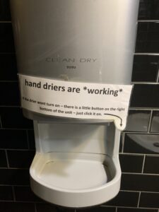 bathroom hand dryer poor design with printed sign front view